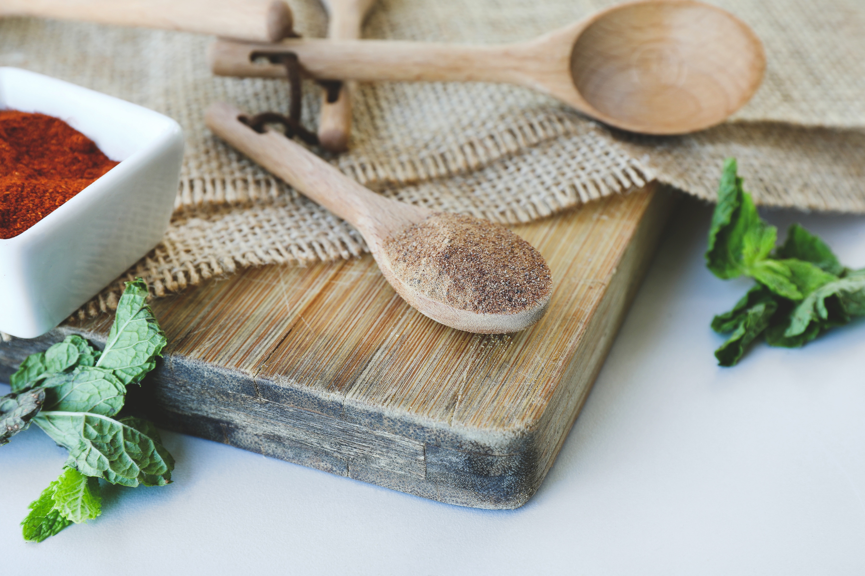Wooden spoon filled with amla powder and other herbs on cutting board