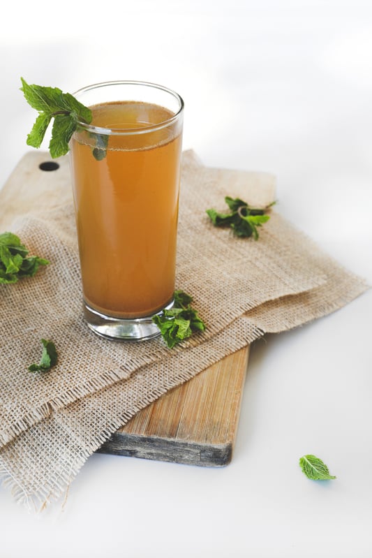 Tall glass with amla drink sitting on burlap napkins on cutting board