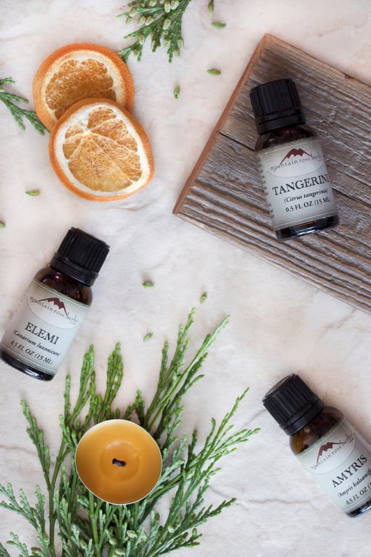 Variety of essential oils, elemi essential oil, tangerine essential oil, and amyris essential oil laying out on counter