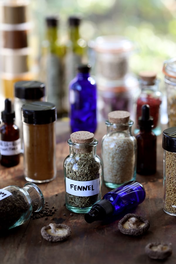 Upcycled jars for home apothecary storage, full of herbs and spices like fennel.