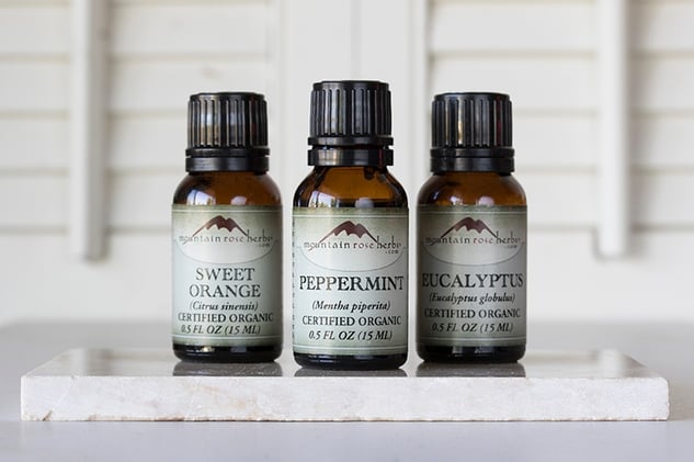 Peppermint, eucalyptus, and sweet orange essential oil bottles next to each other standing upright