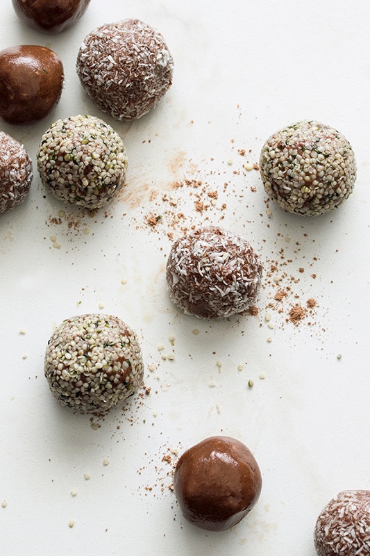 Chocolate bites rolled in coconut and hemp seeds with chocolate powder on counter