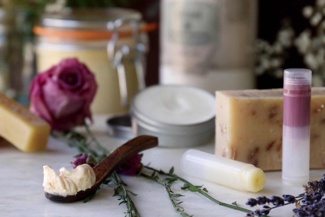 A scoop of babassu oil surrounded by skin care products made with babassu