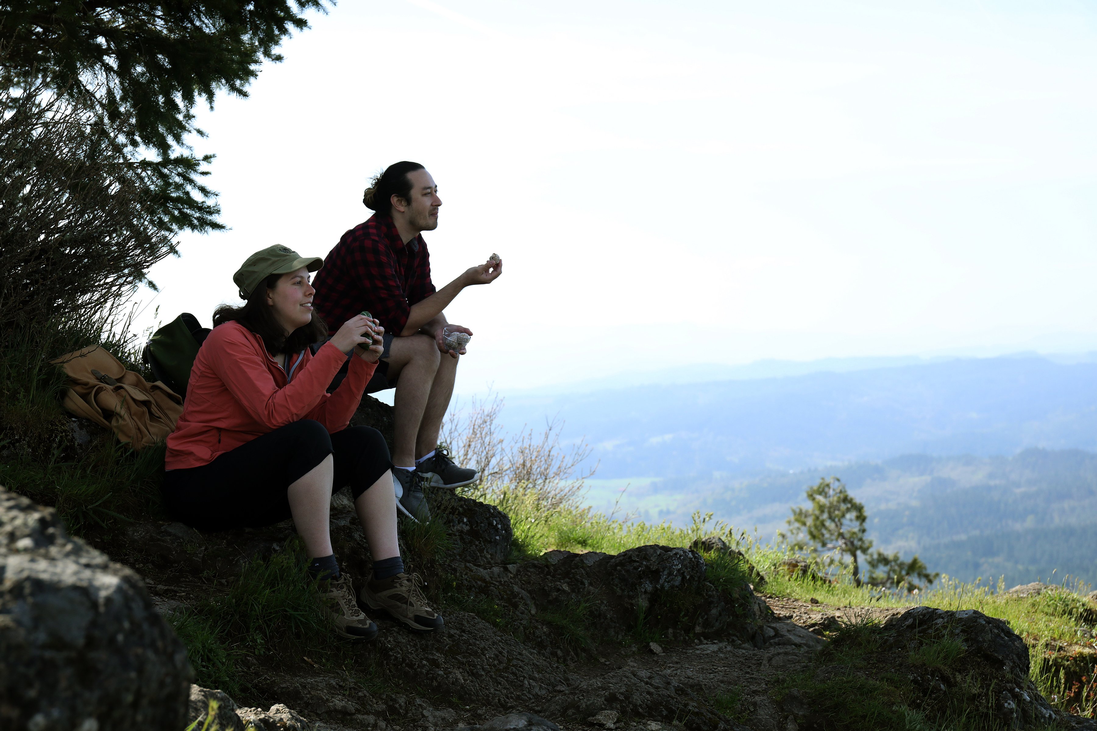 Hikers taking a break at the peak of a mountain in scene Oregon. Enjoying vegan hiking snacks and low waste outdoor leisure. 