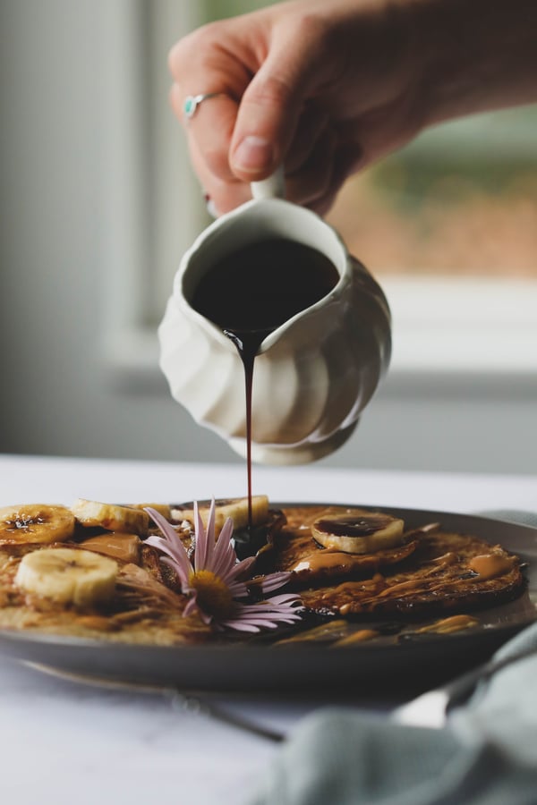 Pouring syrup over banana pancakes. 