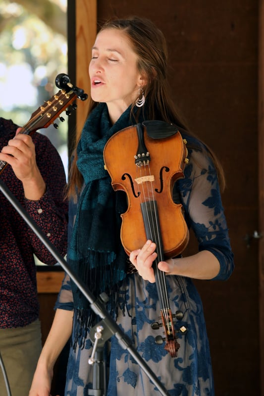 Performer with a violin singing in a band during an event.