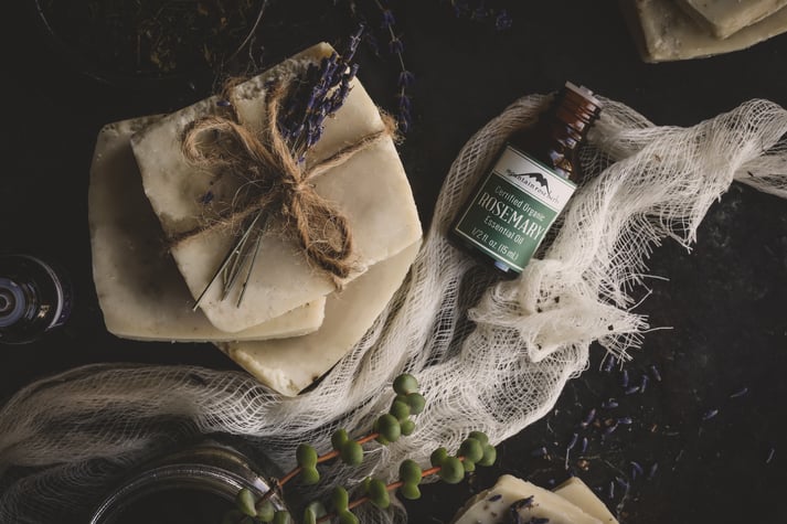 Homemade Shampoo Bars tied with twine and a bottle of rosemary essential oil