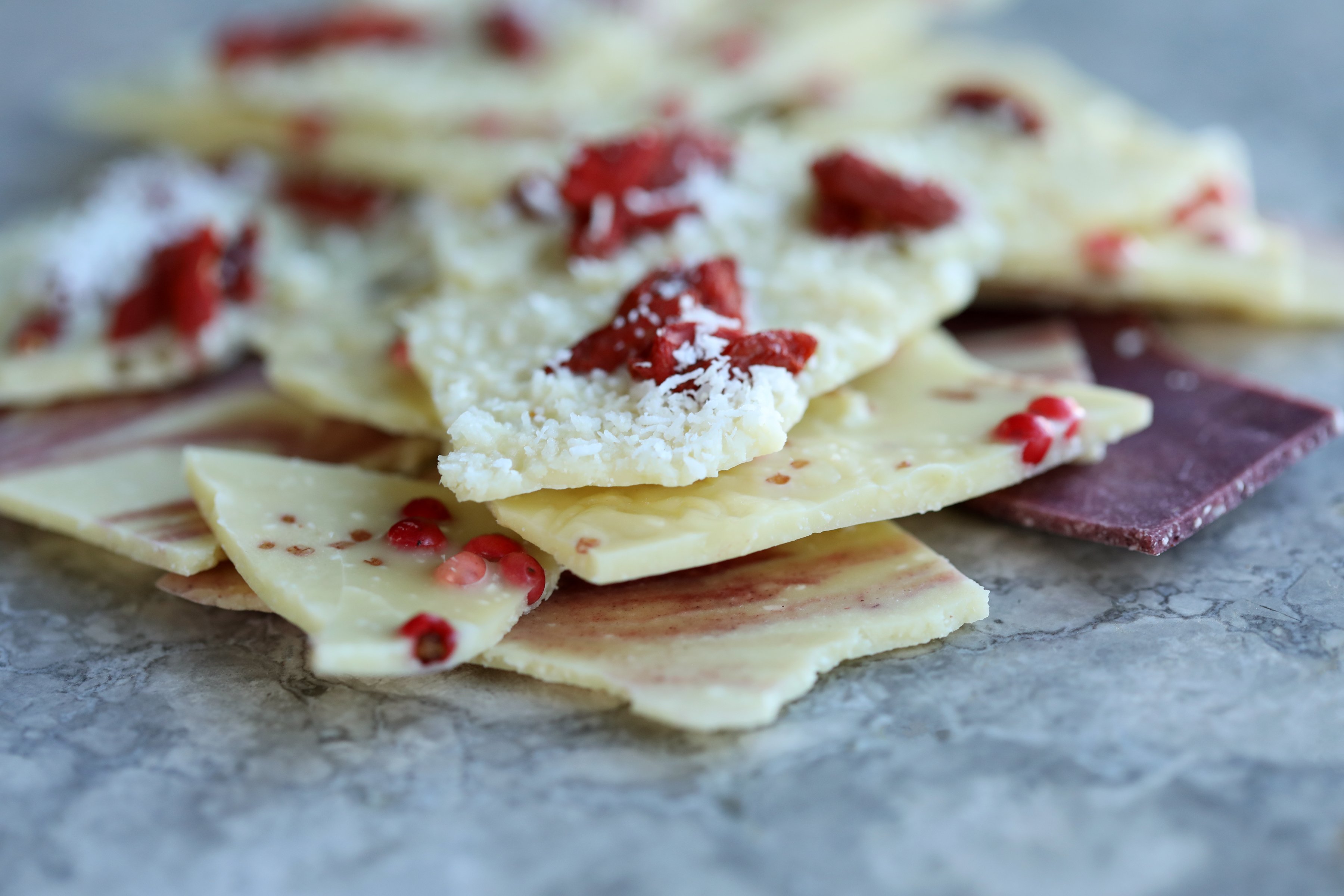 Different sized and shaped pieces of white chocolate with pink toppings and coconut flakes. 