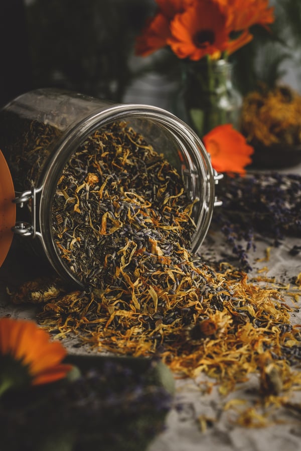 A mixture of herbs spilling out of a pantry jar.