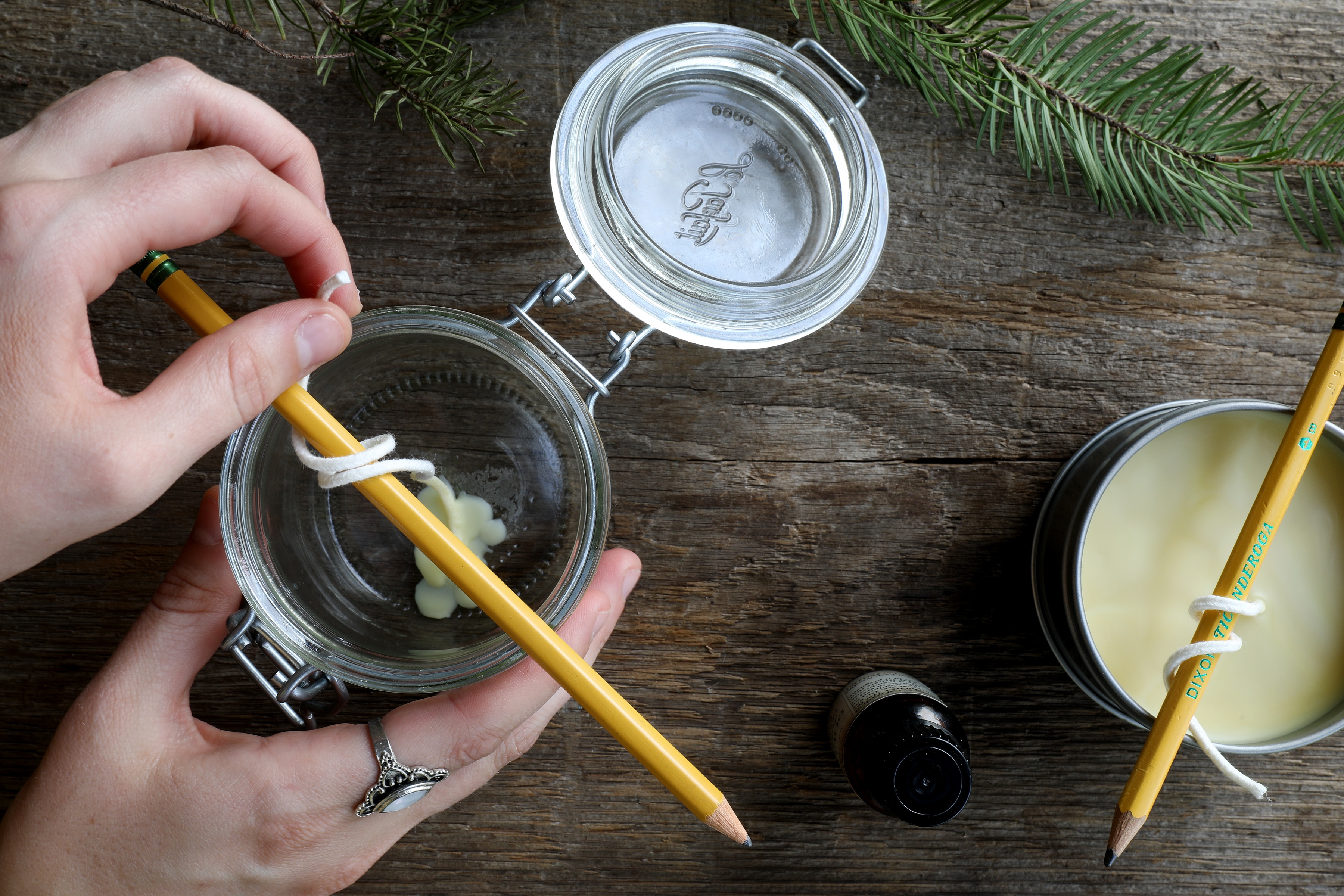 Hands making candles in jars and tins