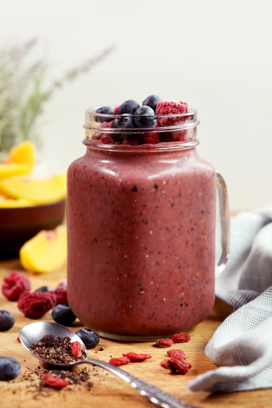 Berry smoothie glass topped with fresh strawberries and blueberries.