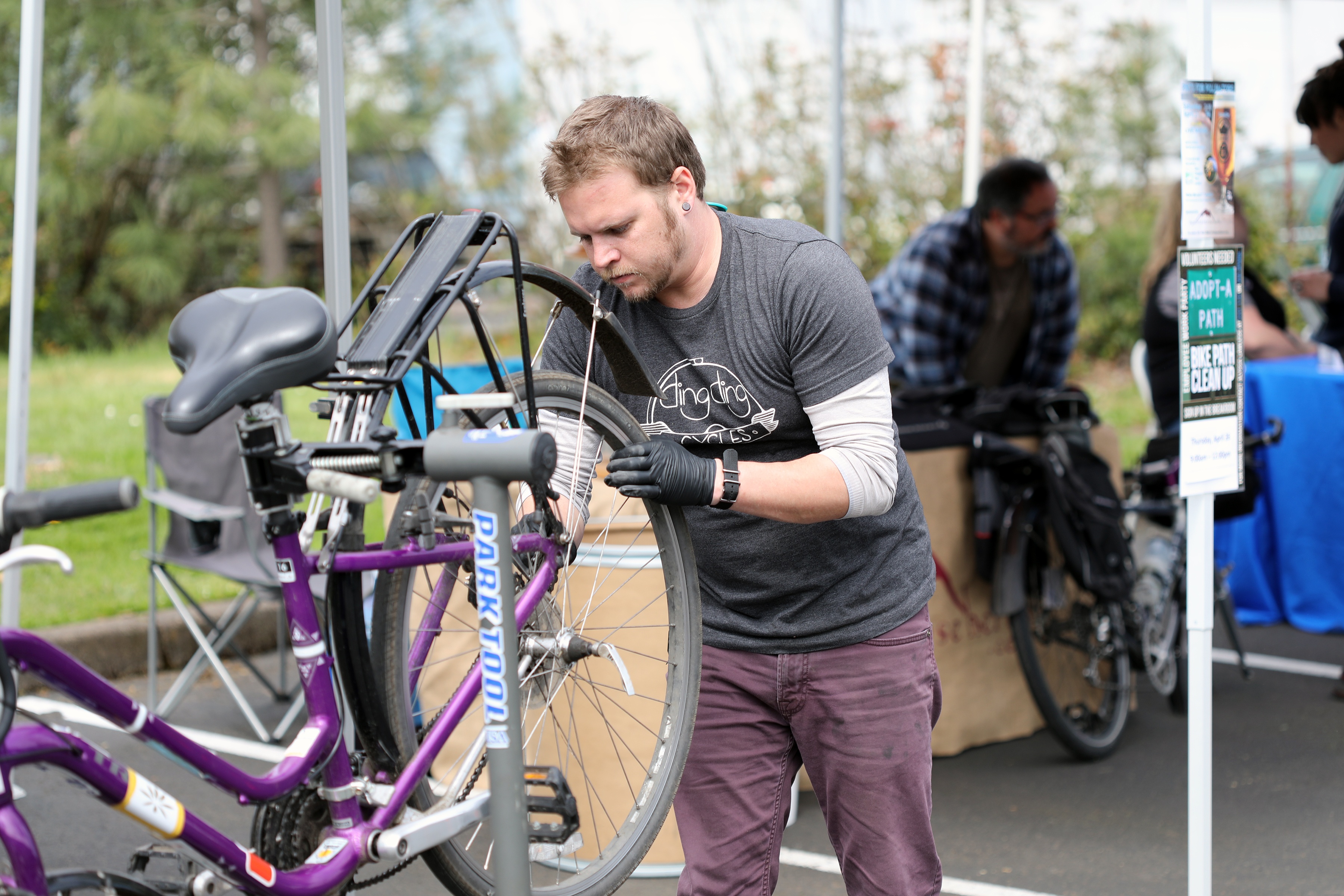 Person holding back tire of bike making adjustments for bike tune up