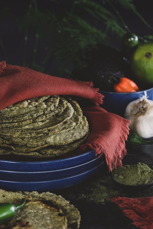 Stack of homemade green tortilla wrapped in cloth. 