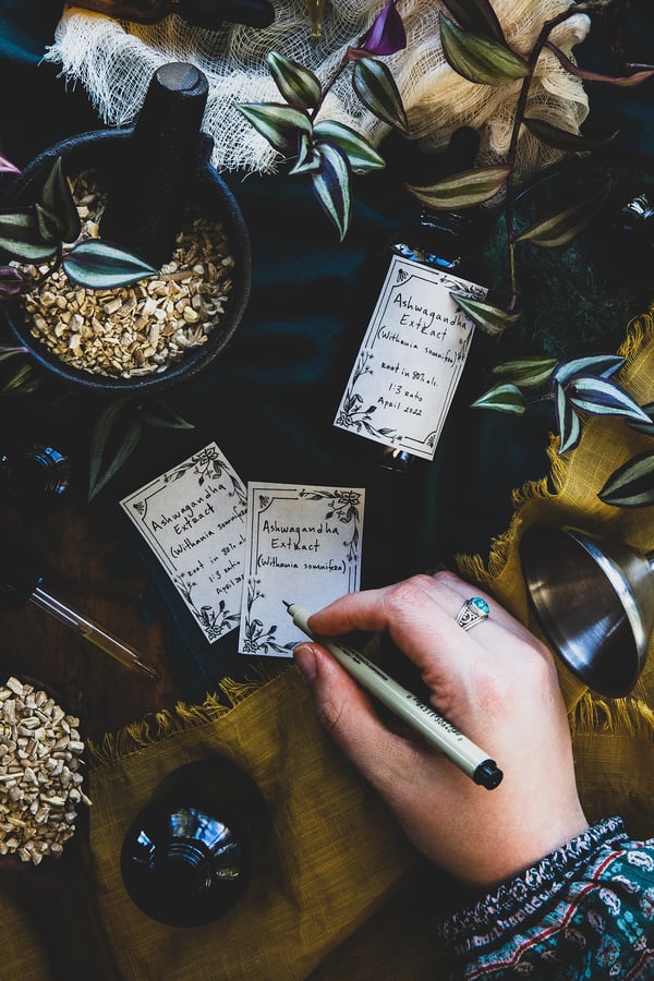 An overhead photo of someone labeling a homemade ashwagandha extract