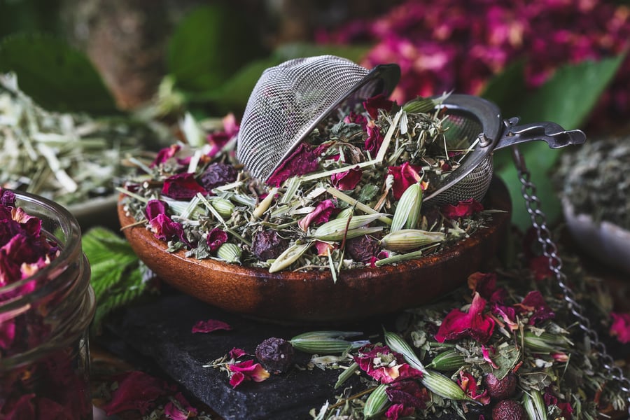 A blend of herbal tea in a wooden bowl with a tea ball in it