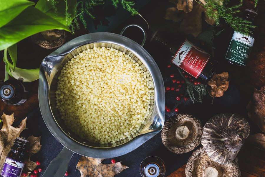 A double boiler with beeswax sits surrounded by ingredients for wax melts