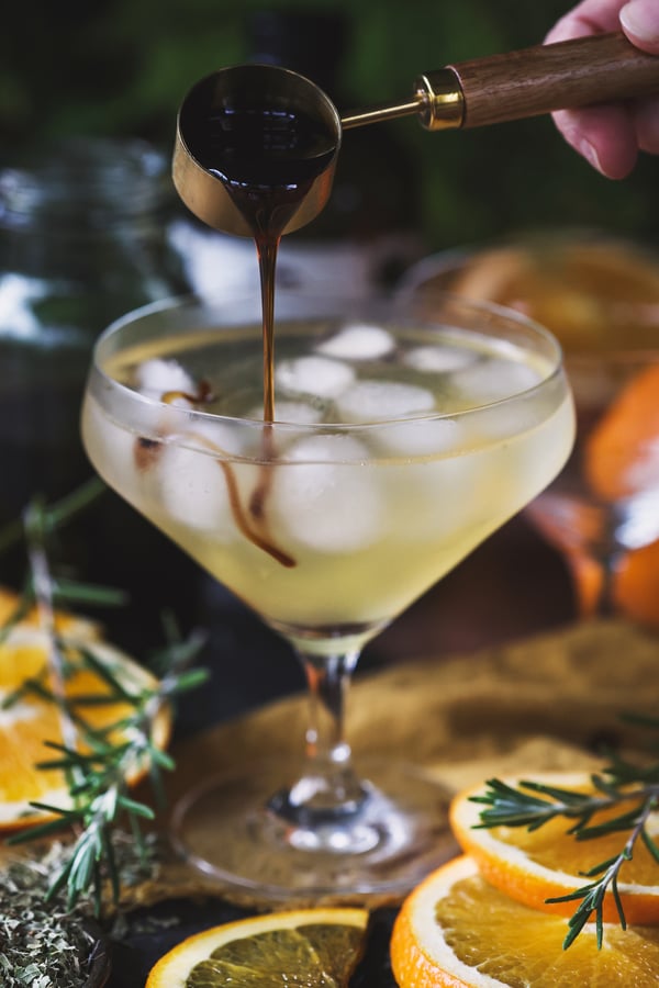 A frosty mocktail with balsamic oxymel being drizzled into it