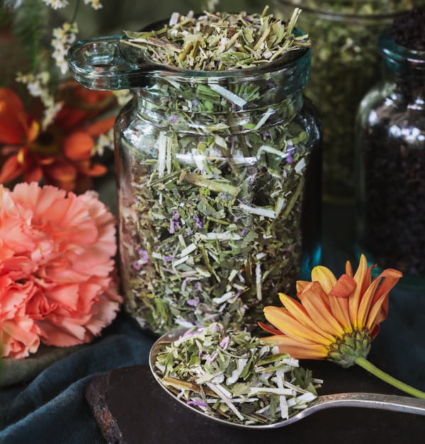 A jar of dried bee balm sits out beside a spoonful