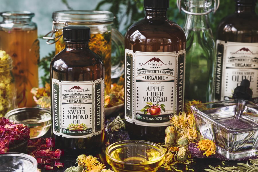 An assortment of bodycare solvents with dried herbs around them