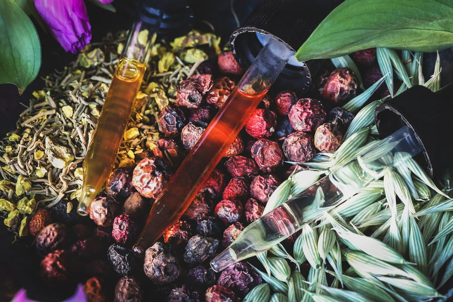 An assortment of herbal extracts in droppers surrounded by herbs