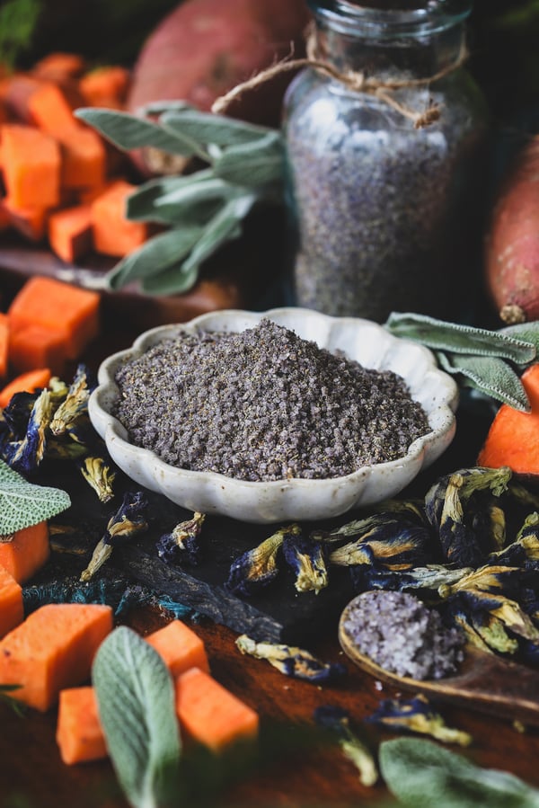 A bowl of blue butterfly finishing salt with sweet potatoes in the background