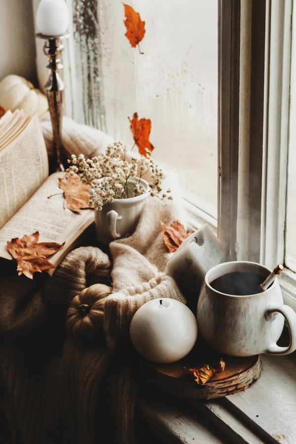 Cozy image of a book, mug of tea, and candle. 