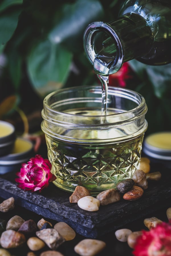 Castor oil is being poured into a small jar