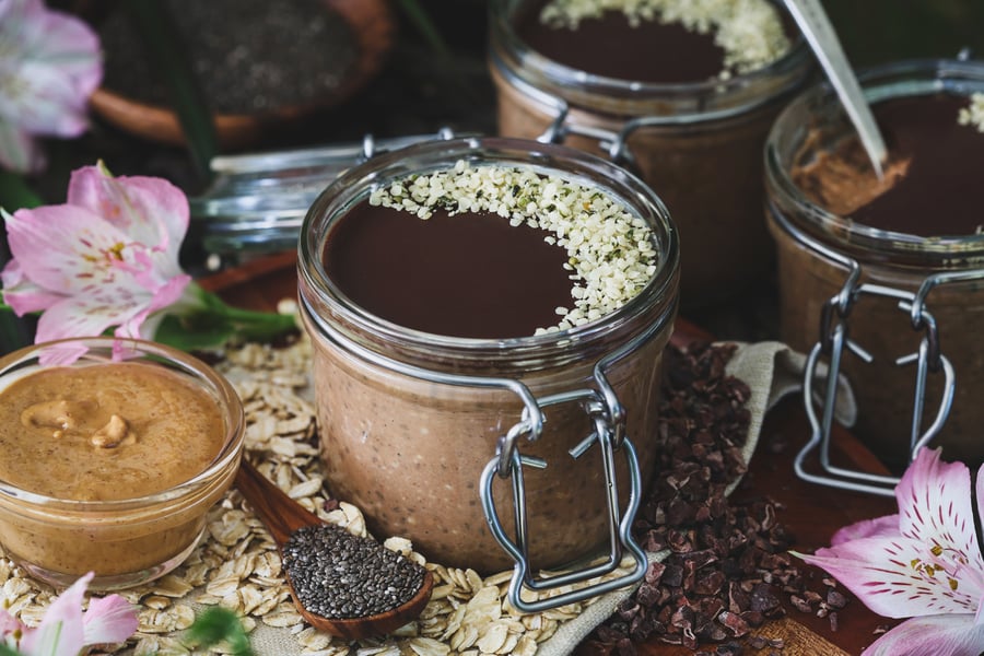 A jar of blended oats topped with hemp seeds sits among ingredients