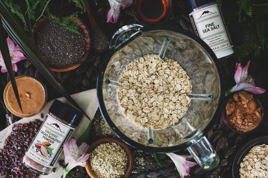 Ingredients for blended oats sit out near a blender with rolled oats in it