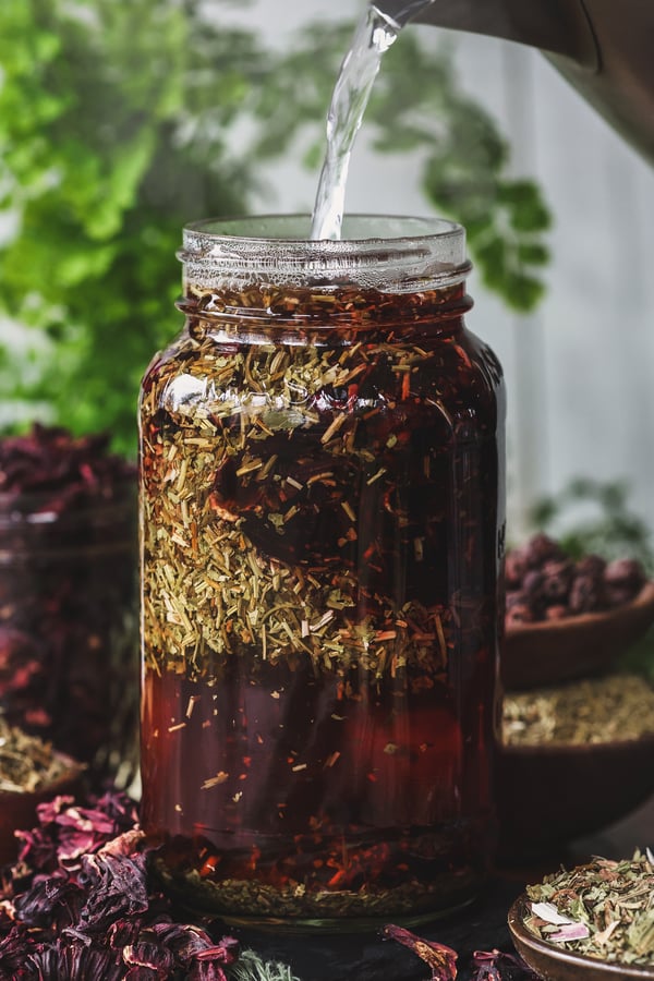 An circulatory supporting herbal infusion being made in a jar with dried herbal ingredients around it