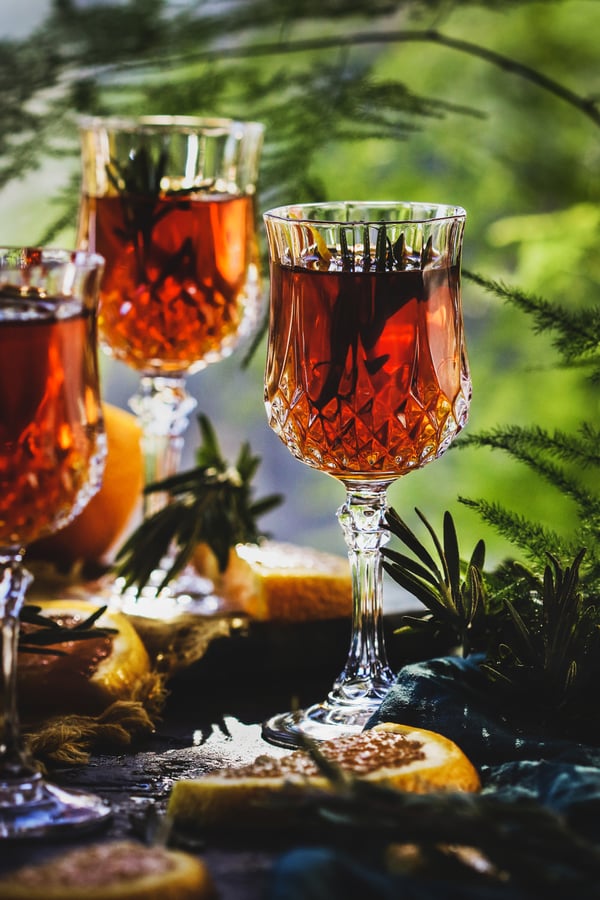 Homemade cordial in glasses surrounded by botanicals