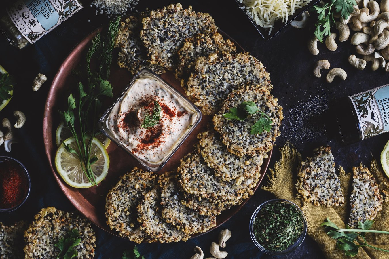 A plate of homemade seed crackers and cashew sour cream herb dip
