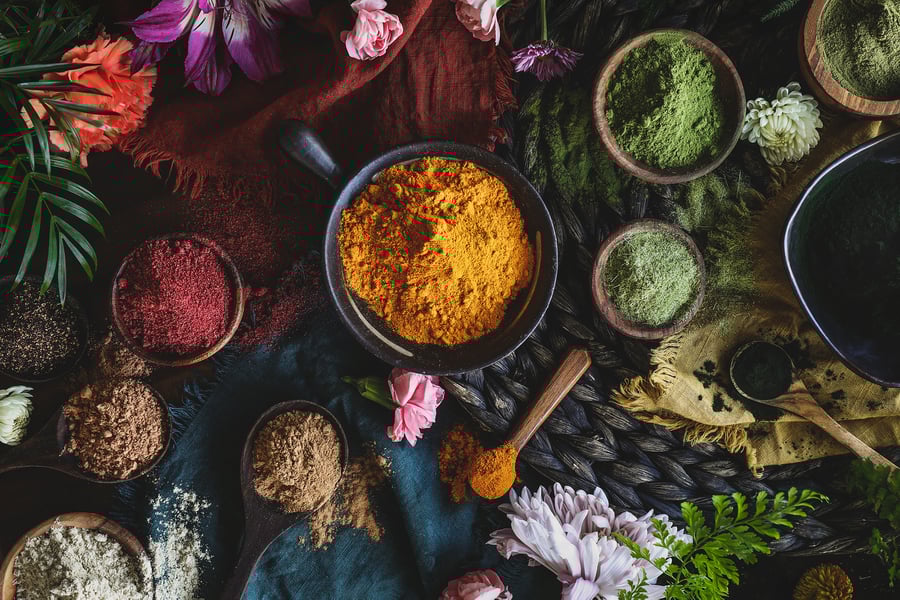 An overhead photo of colorful herbal powders in bowls