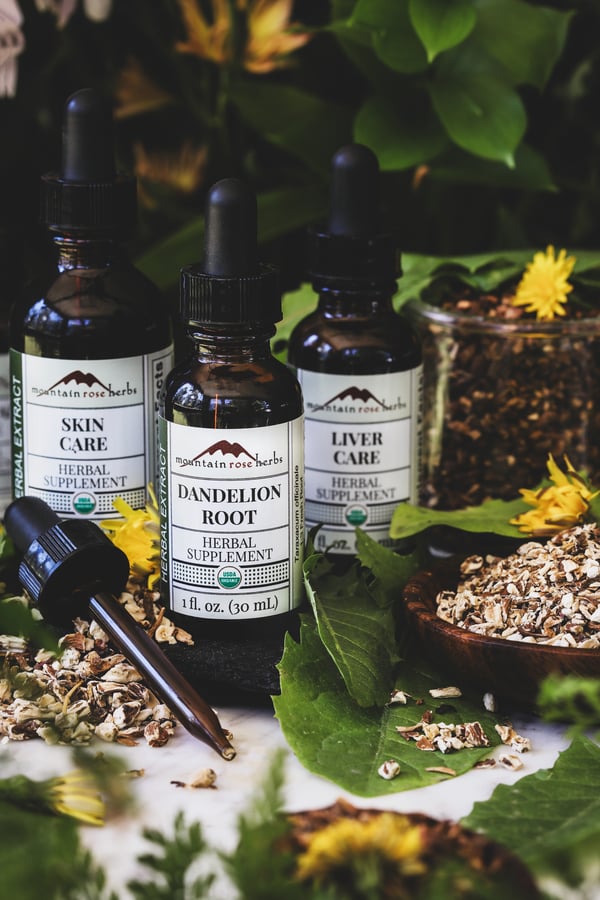 An assortment of Mountain Rose Herbs' dandelion products sitting amongs leaves and flowers