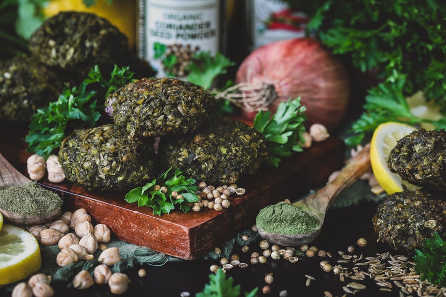 Herbal falafel sit out on a board next to spinach and nettle powder