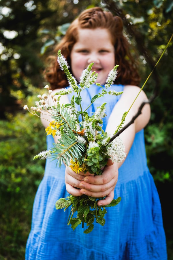 A happy child holding herbs and flowers