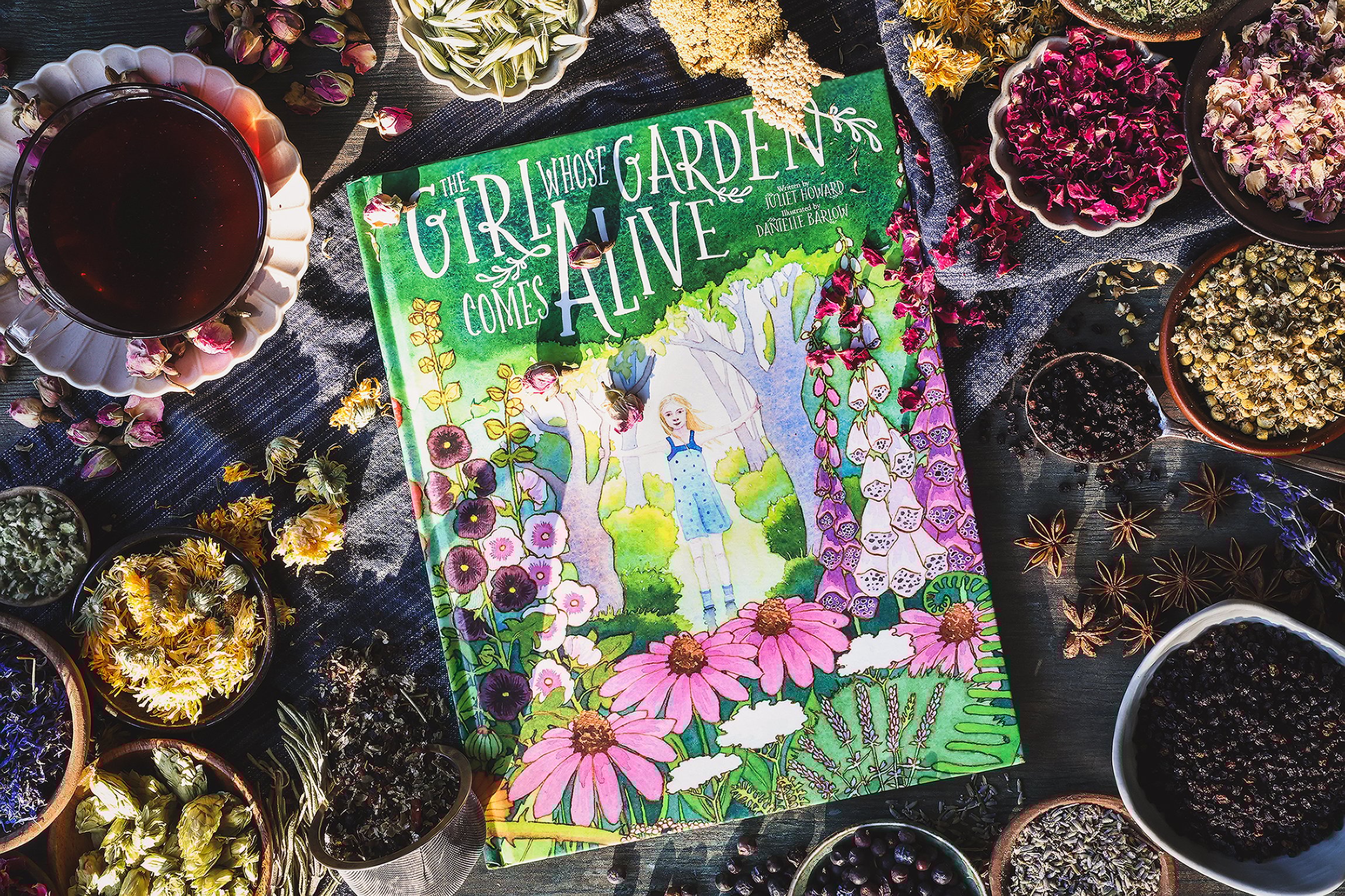 An overhead photo of a children's activity book with tea and dried herbs around it