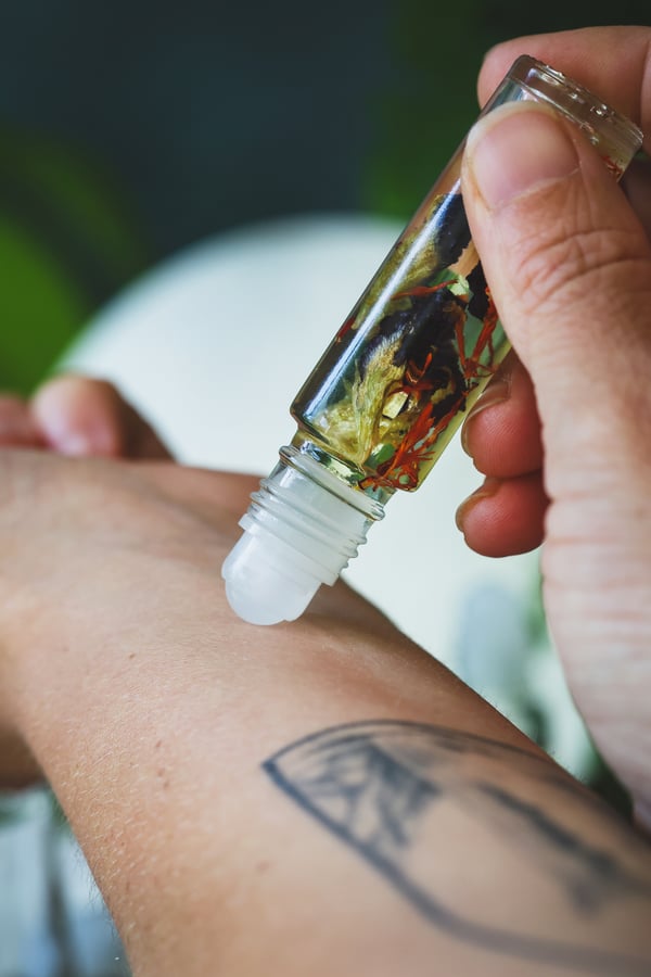 A bottle of roll on perfume being applied to a wrist
