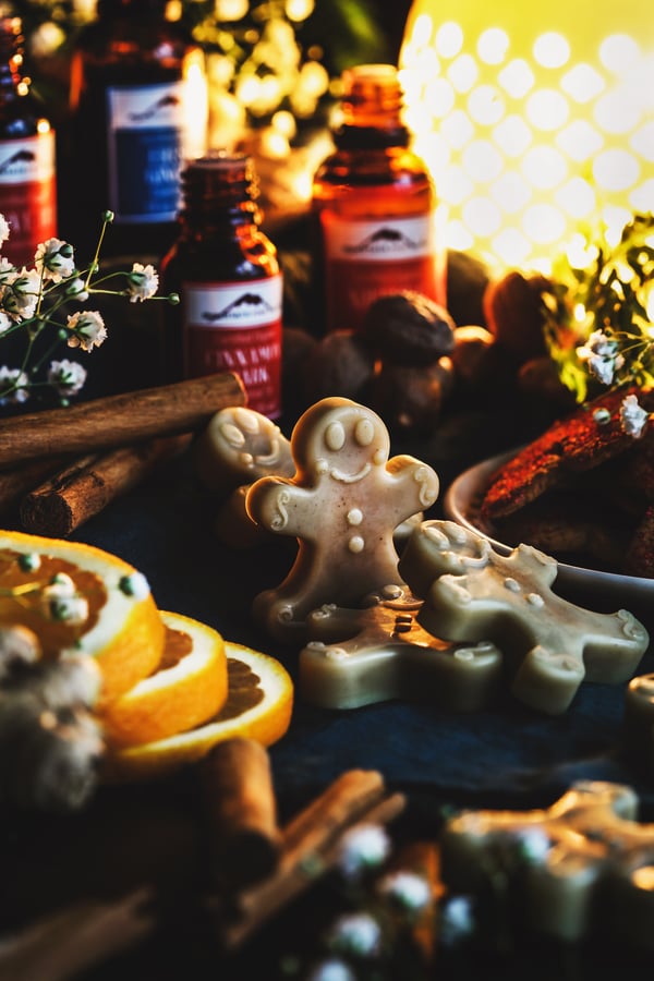 A ginger bread man wax melt stands amongst a festive bounty.