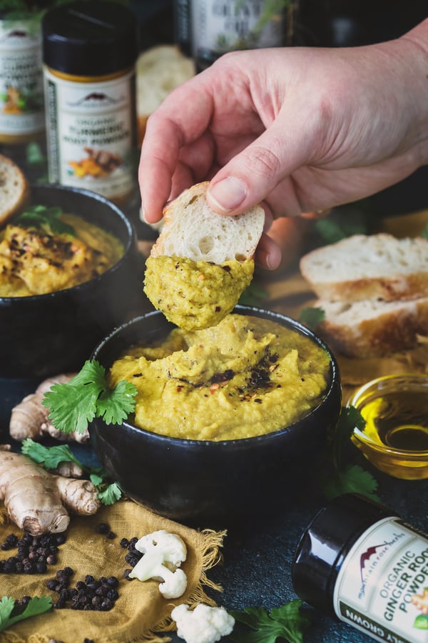 A bowl of golden soup with bread being dipped into it