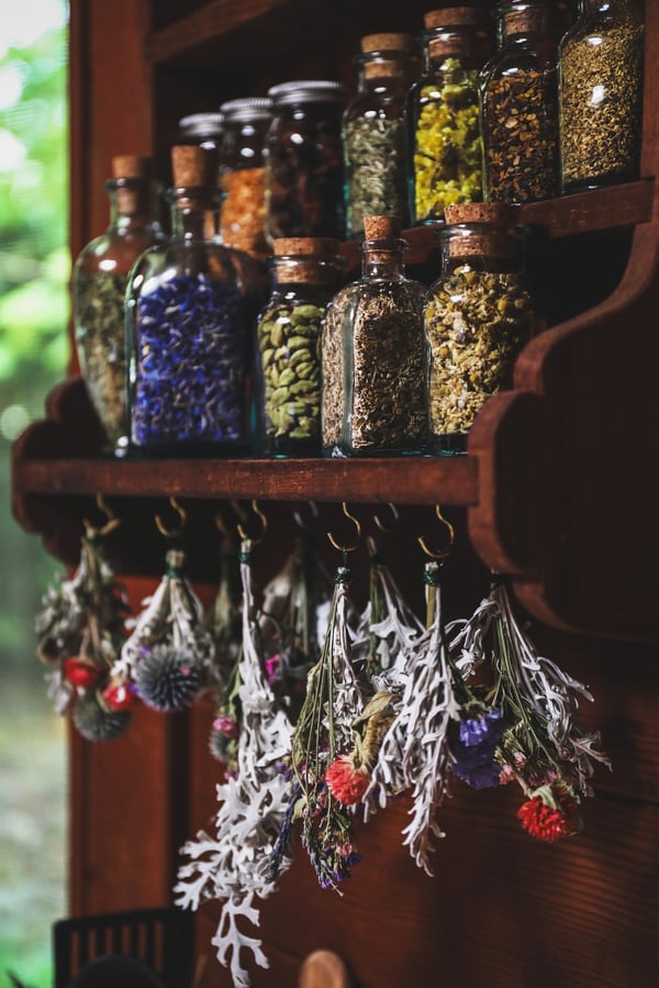 A wooden shelf with jars of dried herbs on it