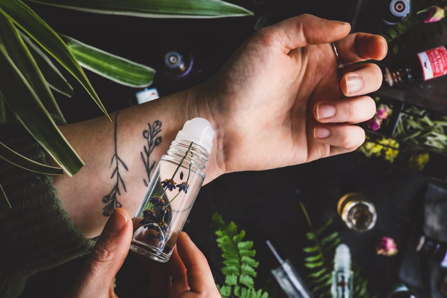An overhead photo of someone applying an essential oil perfume to their wrist