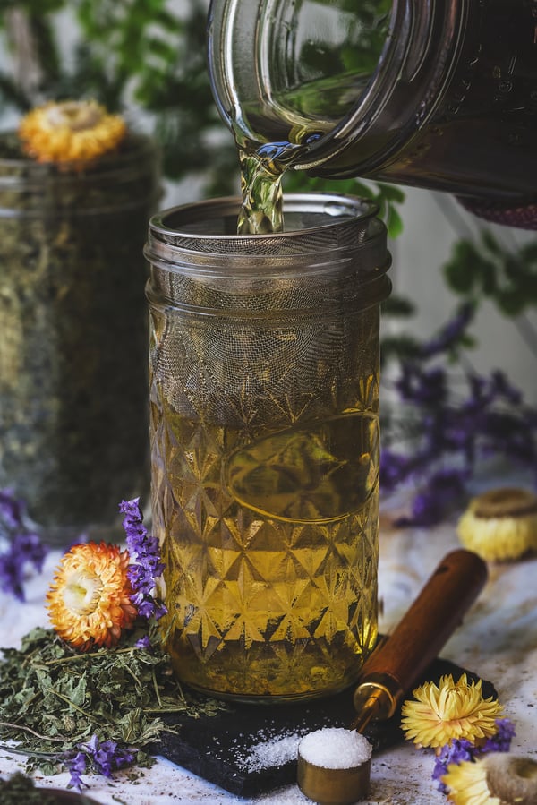 Lemon balm and nettle infusion being strained into a jar