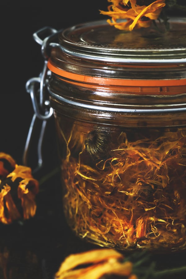 A jar of dried calendula infusing in oil