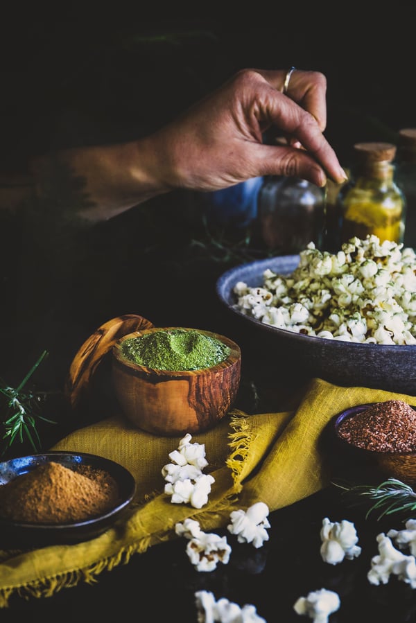 An herbal powder blend is sprinkled on a bowl of popcorn