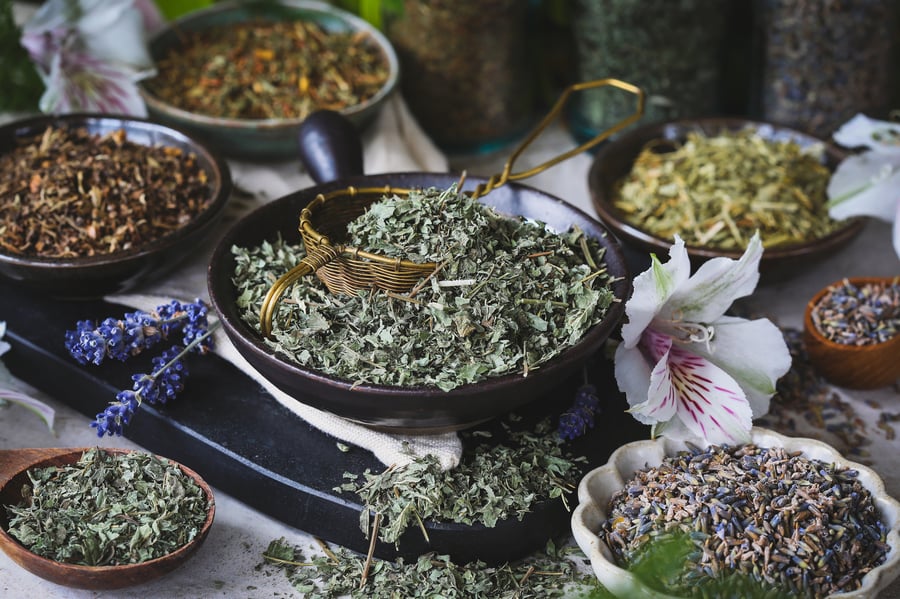 Assorted dried herbs that support emotional well being in bowls on counter top