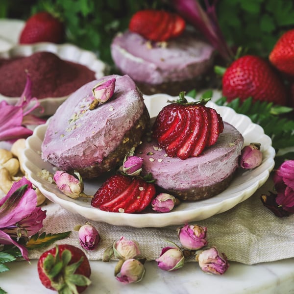 Two hibiscus rose cheesecakes topped with strawberries and hemp seeds