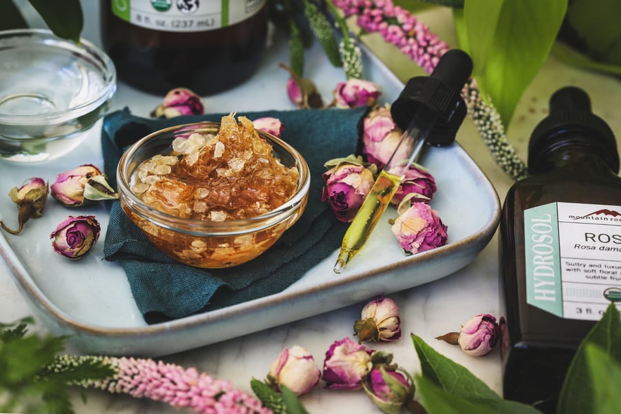 Ingredients and fabric for sheet mask lay out among rose buds