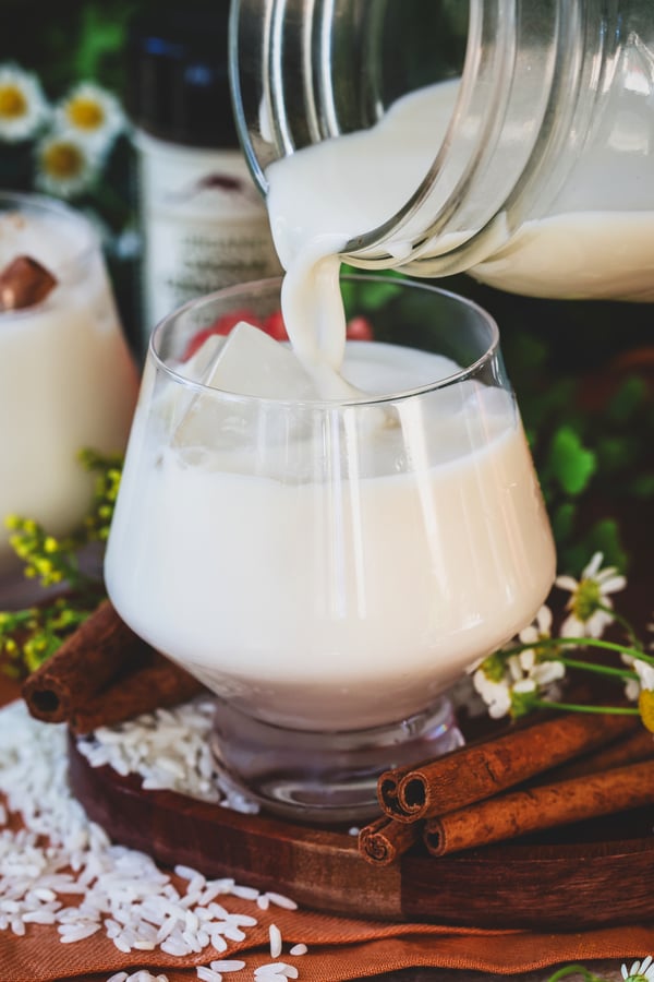 Fresh homemade horchata being poured over ice cubes into glass