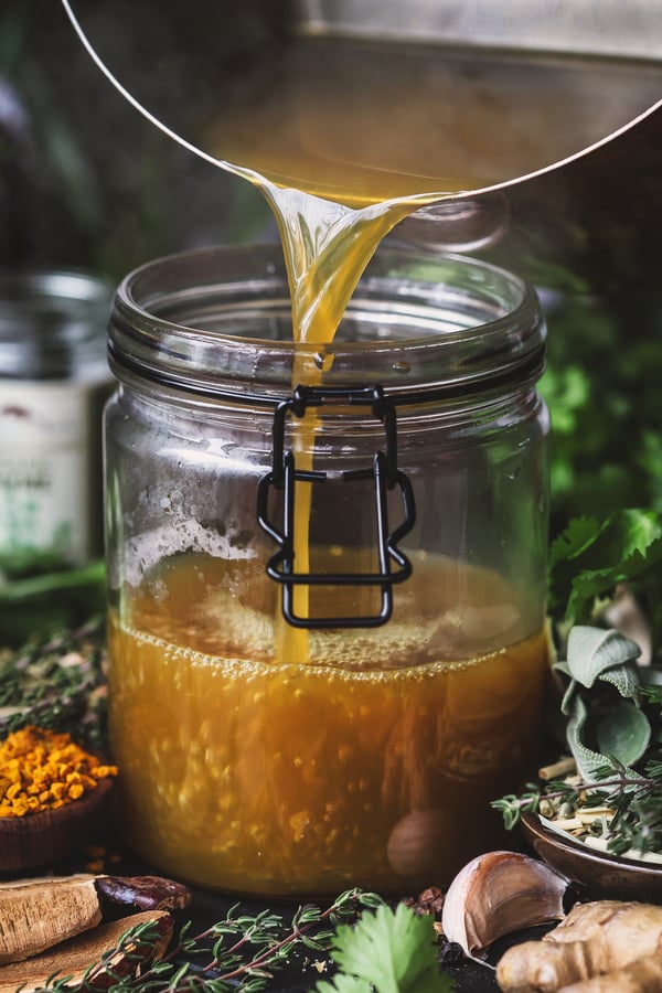 Steamy broth is poured in a jar for storage